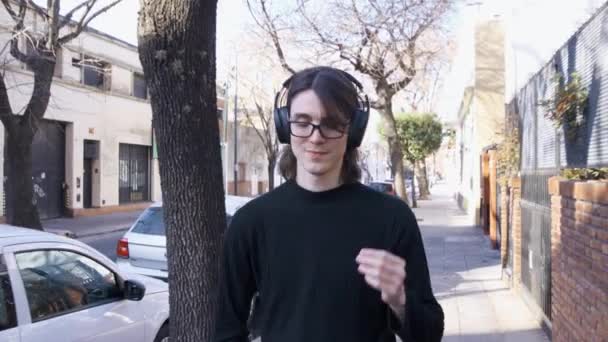 Young Man Glasses Headphones Walking Listening Music Street Smiles — Stockvideo