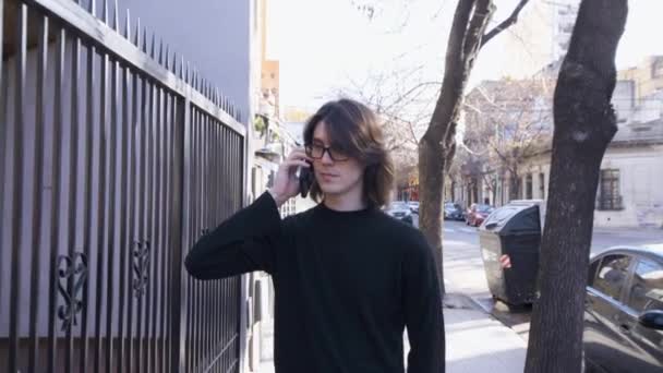 Young Man Glasses Walking Street Talking His Mobile Phone Reverse — Stockvideo