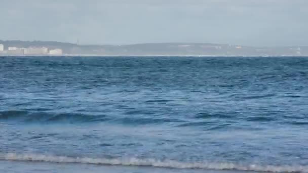 カスカイスビーチを背景にコスタ カパリカと一緒にカルカベロスで夏の日に水と波に逃げる マーティム砦の近くだからフリオ — ストック動画