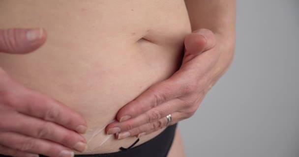 Close up gimbal shot of woman applying moisturizer to her belly