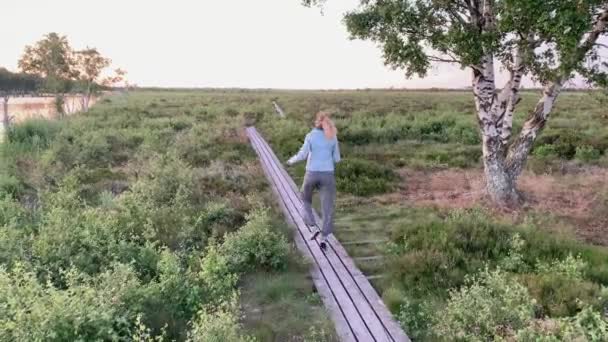 Happy Blonde Woman Skipping Wooden Plank Pathat Sunset Nature — Stockvideo
