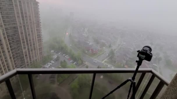 白い霧が通り過ぎる街の高層住宅のバルコニーに三脚に設置されたカメラの概要 新居アパート — ストック動画