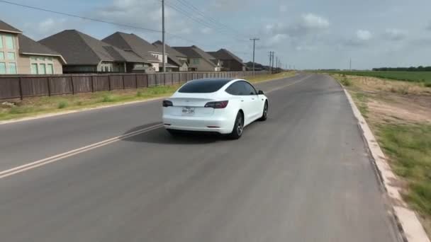 Aerial Tracking Rear Side White Tesla Model Driving Rural Texas — Vídeo de Stock