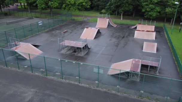 空の閉じた公共の遊び場でフェンスで囲まれたスケートパークランプの上を飛ぶ空中ビュー — ストック動画