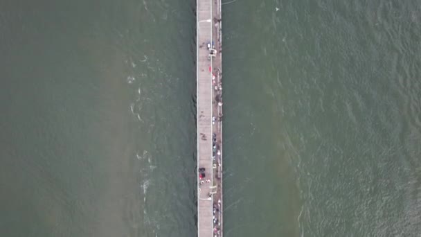 一架无人驾驶飞机在一个木制渔港上空盘旋 人们享受着多云的早晨 摄像机 笔直地朝下倾斜在长长的码头上 — 图库视频影像