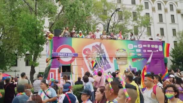 プライドパレードの出演者を運ぶパーティーバス街に沿って大群衆を過ぎましたフアレスメキシコ市でレインボーフラッグを振っています スローモーション — ストック動画