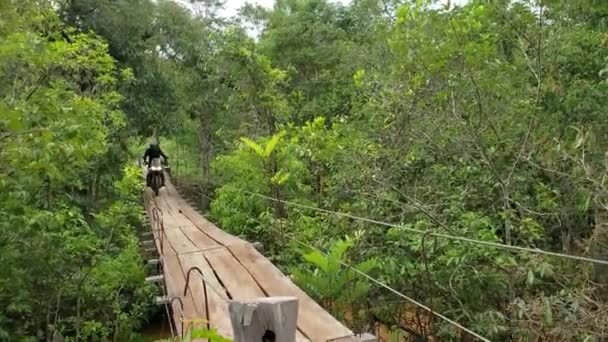 摩托车手穿过乡间轻便的缆索悬索桥 — 图库视频影像