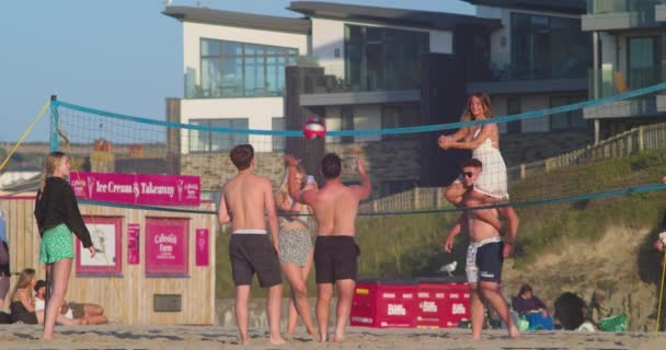 Młody Mężczyzna Niosący Dziewczynę Ramionach Podczas Gry Siatkówkę Plaży Perranporth — Wideo stockowe