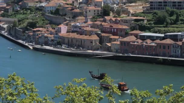 ポルトガルの穏やかな水を航海する伝統的な木製のボートを備えた風光明媚なドゥオーロ川の風景と並ぶ住宅建築物 スローパンショット — ストック動画