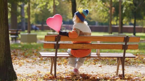 Mladá Žena Srdcovým Balónem Sedí Lavičce Mává Posílá Polibky Podzimní — Stock video
