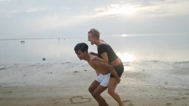 Young Thai Man Mature Caucasian Woman Couple Piggyback Ride Beach — Stock Video