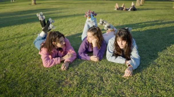 Three Girls Wearing Roller Skates Lie Lawn Sunlight Talk – stockvideo