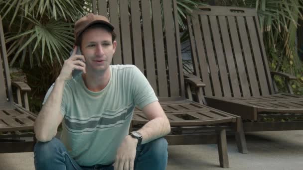 Telefonda Konuşan Bir Adam Plaj Sandalyeleri Tropikal Bitkilerin Yanında Duygu — Stok video