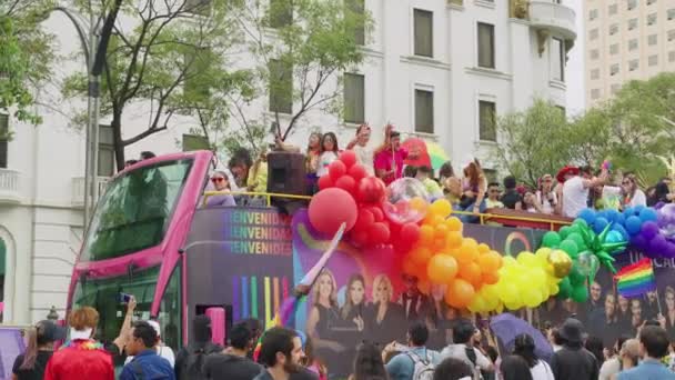 Bus Mit Regenbogenfarbenen Luftballons Fährt Menschenmassen Entlang Der Avenue Juarez — Stockvideo