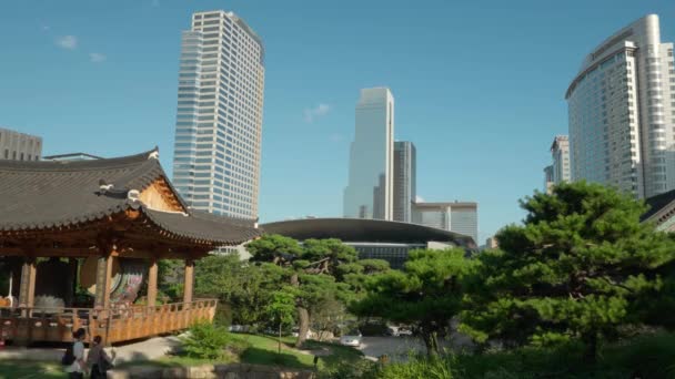 奉恩寺 大鼓と大鐘を背景に高層ビルが立ち並ぶ韓国の伝統館の近くを歩く人々の時間の経過 — ストック動画