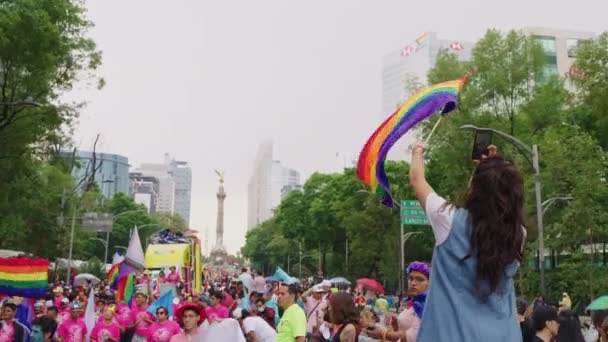 Women Waving Rainbow Flag Whilst Holding Phone Pride Parade Approaching — Stok Video