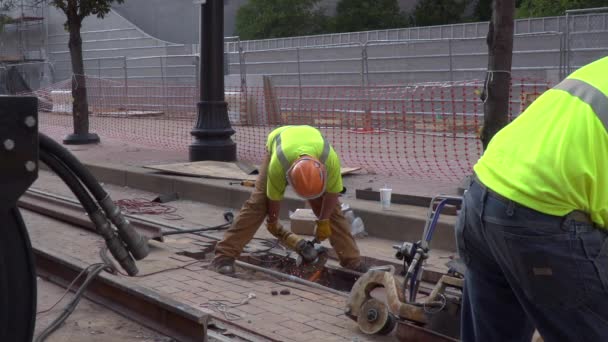 一个建筑工人在一个城市里研磨新的钢轨的慢镜头 当另一个工人站在前头时 火花飞得很慢 — 图库视频影像