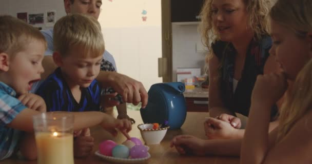 テーブルに座ってカラフルなイースターエッグを染色して楽しい家族 — ストック動画
