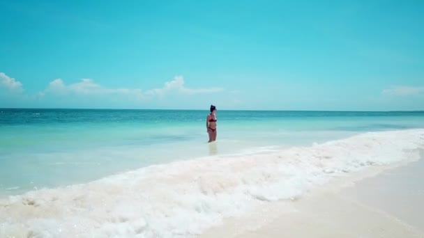 在肯尼亚海岸 一个迷人的女孩穿着红色泳衣 穿着白色沙滩上飞溅的浪花 大范围射击 — 图库视频影像