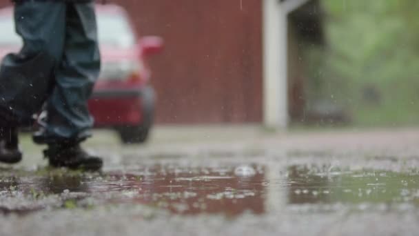 スローモーション ウェットウェザーギアの子供は大雨の中を歩く — ストック動画