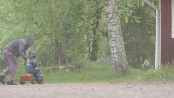 Yavaş Hareket Yağmurda Çocuğunu Renkli Bir Bisiklete Iten Bir Ebeveynin — Stok video