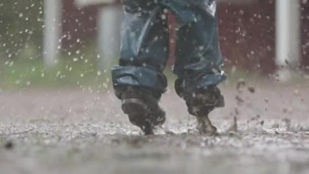 Low Motion Uma Criança Salta Uma Poça Lamacenta Durante Chuva — Vídeo de Stock