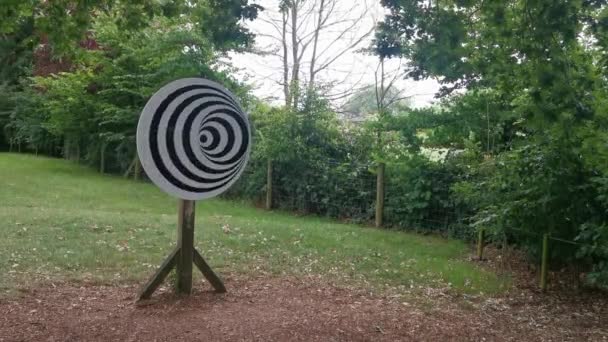 A Spinning Spiral Optical Illusion on a Wooden Pole in a Park