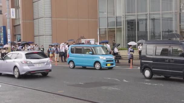 安倍晋三前首相の死後の朝 人々は雨の中で彼の死を尊重するために立ちます — ストック動画