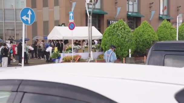 安倍晋三の殺害現場で一人の日本人警察官が雨の中に立つ — ストック動画