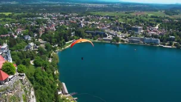 スロベニアの鉄壁のある城のある湖の上の観光客のパラグライダー — ストック動画