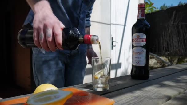 Man Pouring Out Vermouth Glass Lemon Wooden Table Sunny Garden — стокове відео