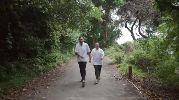 Male Gay Couple Walking Island Walkway Trail Holding Hands Showing — Stockvideo
