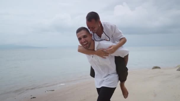 Cheerful Gay Man Giving Piggyback Ride His Partner Beach — Video Stock