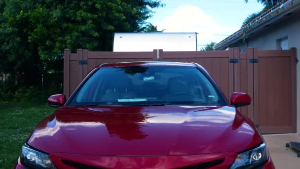 赤い車の上に座っている間 長い髪をしたクールな男 — ストック動画