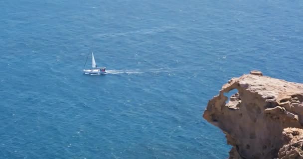 ギリシャのサントリーニ島の岩場の崖の近くの地中海で一人で帆船 — ストック動画