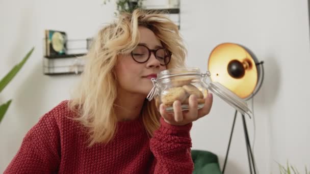 Blonde Young Woman Smelling Cookies Jar Picking One Leaving Back — Stock Video