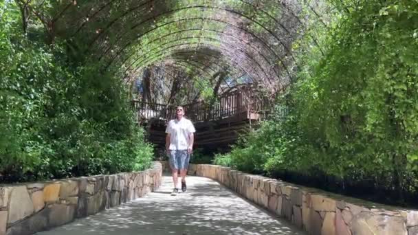 Man Walks Lush Green Plant Tunnel Climbing Foliage Slow Motion — ストック動画