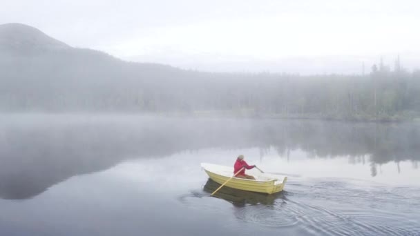 Man Red Jacket Rowing Small Boat Mist Filled Lake — стоковое видео