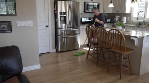 Senior Woman Dusting Sweeping Hardwood Oak Floors Kitchen Tilt — Vídeo de Stock