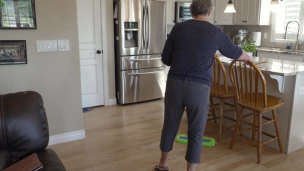 Senior Woman Cleaning Her Hardwood Kitchen Floors Tilt — Stock video