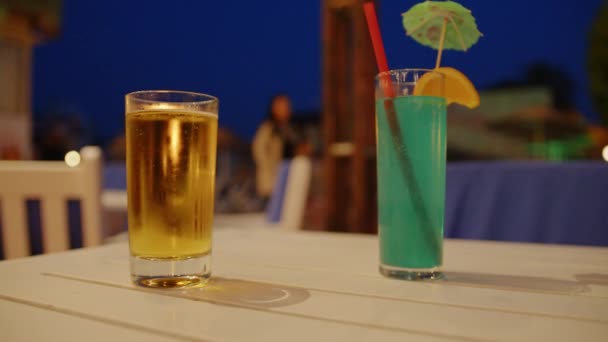 冷たいビールと白カウンターの上に藁と傘で青い飲み物のガラス — ストック動画