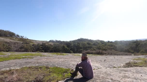 Bushman Sits Granite Mountain Looks Out Accross Australian Bush — Vídeo de Stock