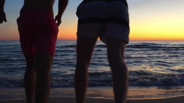 Silhouette Two Friends Running Sea Water Vibrant Sunset Back View — Stockvideo