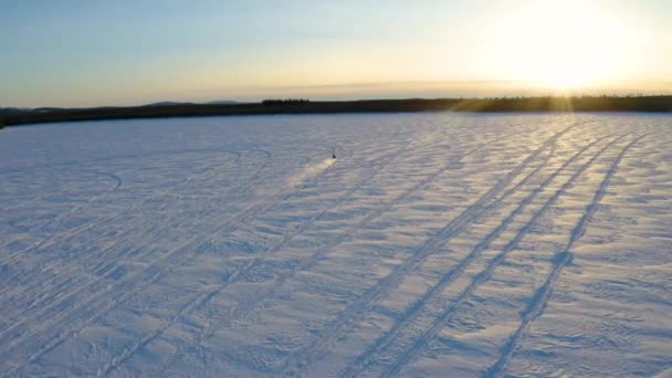 空中景观个人骑雪地摩托穿越雪原荒原朝向日出的风景 — 图库视频影像