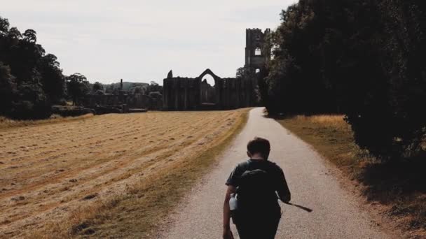 Young Boy Walking Footpath Alone Old Ruined Abbey Summer Day — Stockvideo