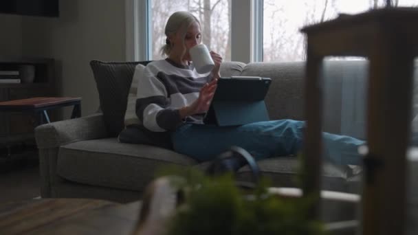 Woman Sitting Couch Front Bay Window Drinking Coffee While Scrolling — Wideo stockowe