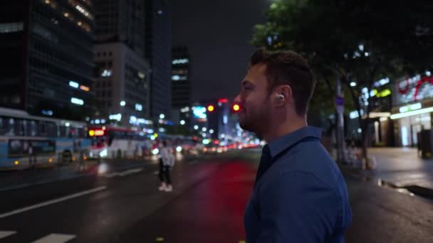 Close Caucasian Man Speaking Wireless Earbuds While Walking Crosswalk Night — Vídeo de stock