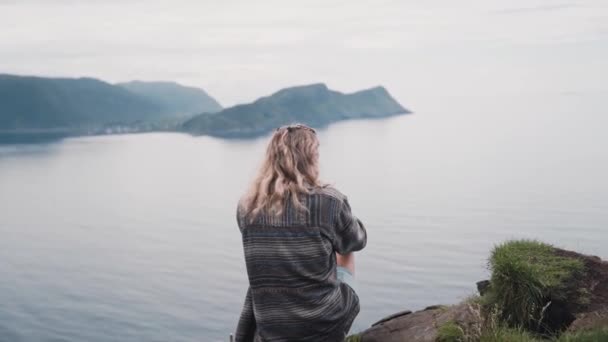 Curly Blonde Woman Sitting Island Cliff Side Overlooking Ocean Water — Stockvideo