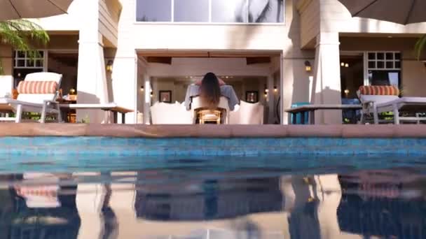 Beautiful Brunette Woman Laying Massage Table Poolside Camera Pushes Pool — стоковое видео