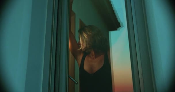 Продумана Жінка Дивиться Захід Сонця Через Вікно Всередині Своєї Квартири — стокове відео